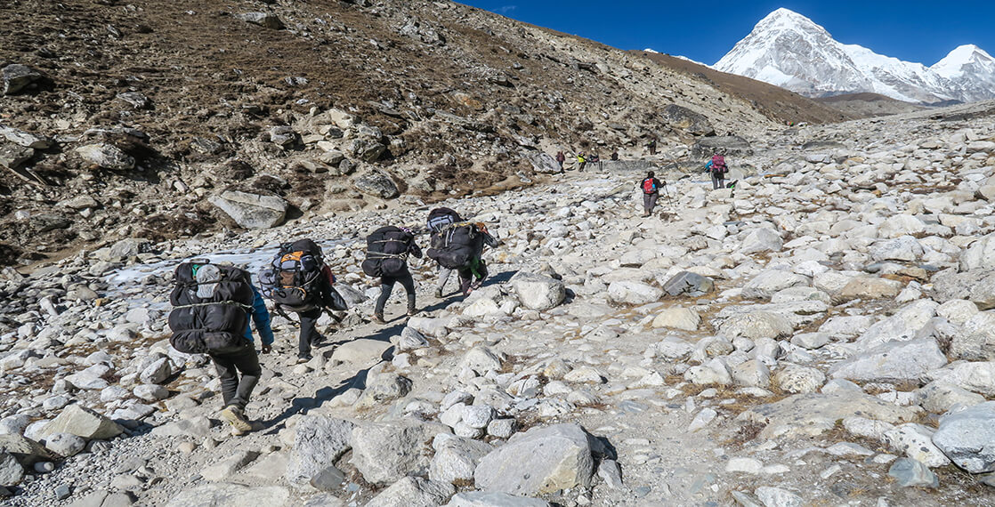 Hikers climbing rocky terrain in mountains.